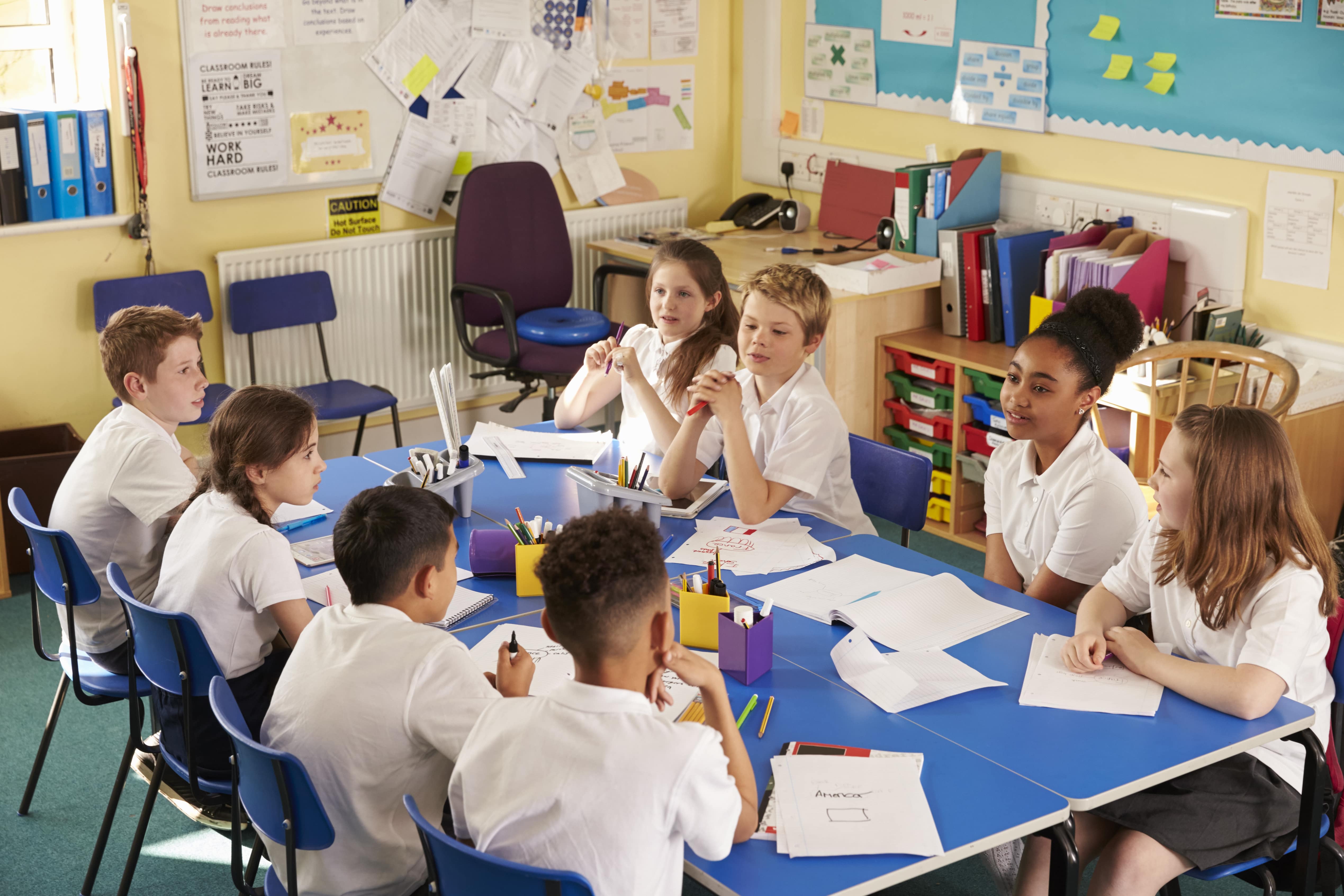 Image of pupils sitting round the table in the classroom discussing ideas.